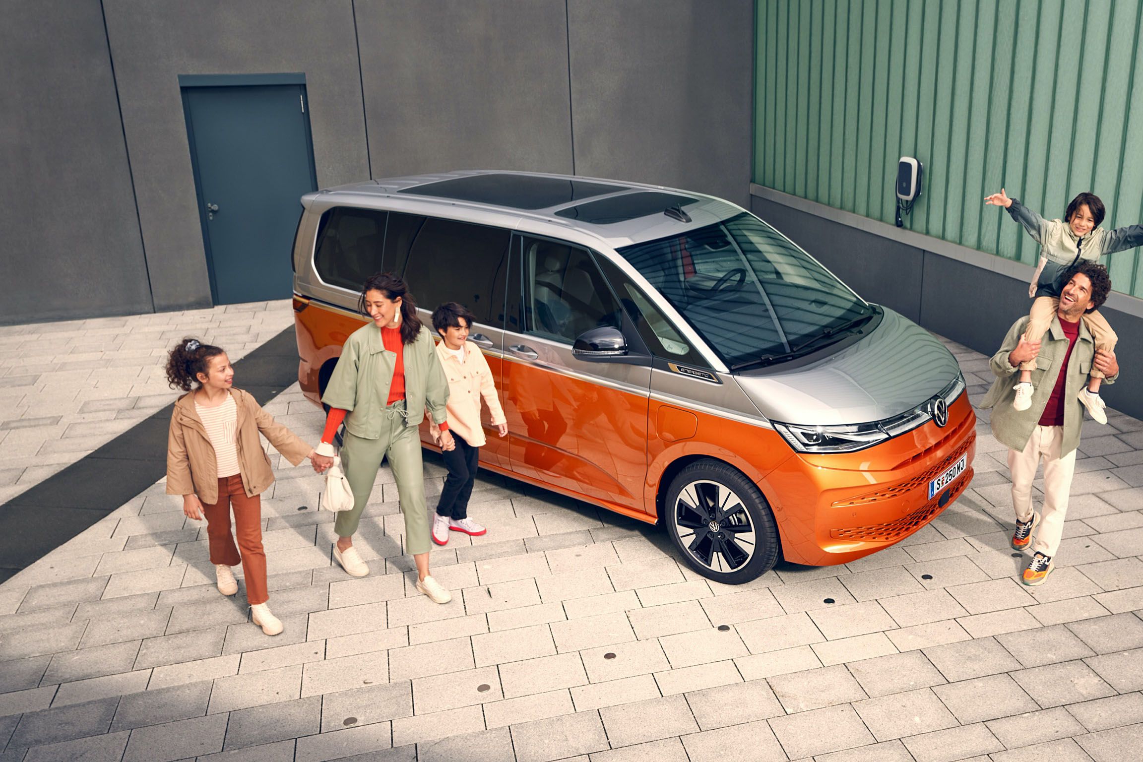 Eine Familie läuft vergnügt neben dem stehenden VW Multivan Energetic T7 2021 her