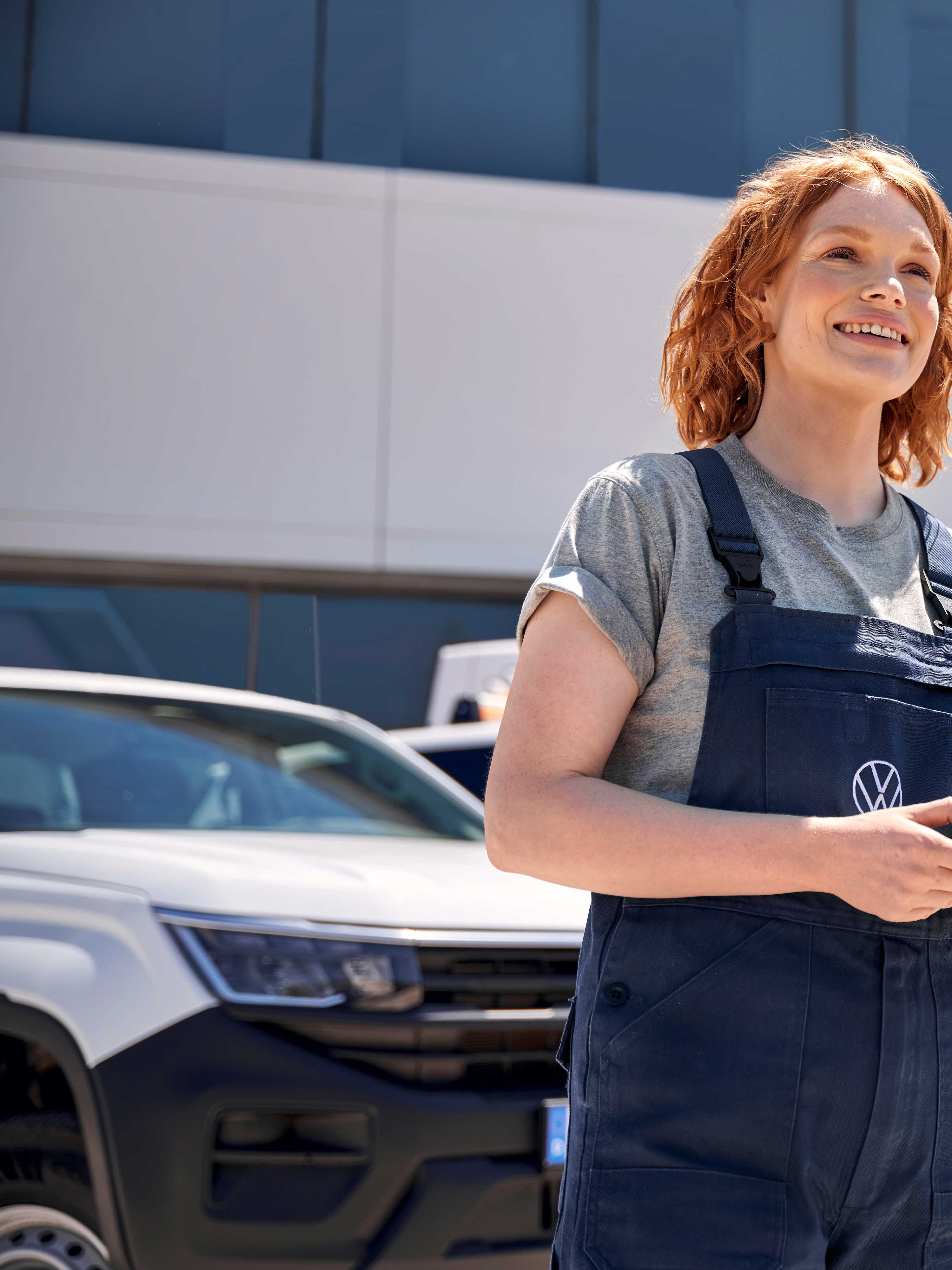 Eine Volkswagen Service Mitarbeiterin vor einem Volkswagen Service Gebäude