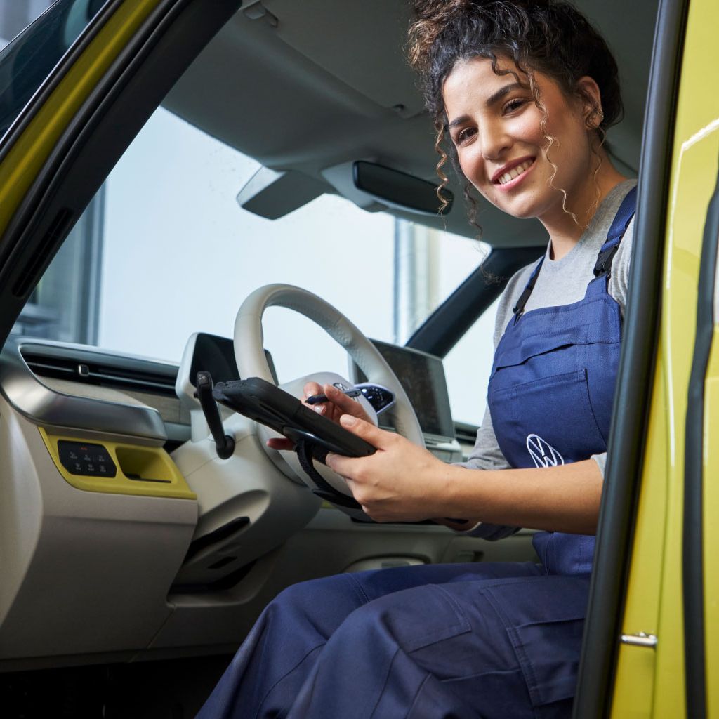 VW Service-Mitarbeiterin im Führerhaus eines VW-Nutzfahrzeuges