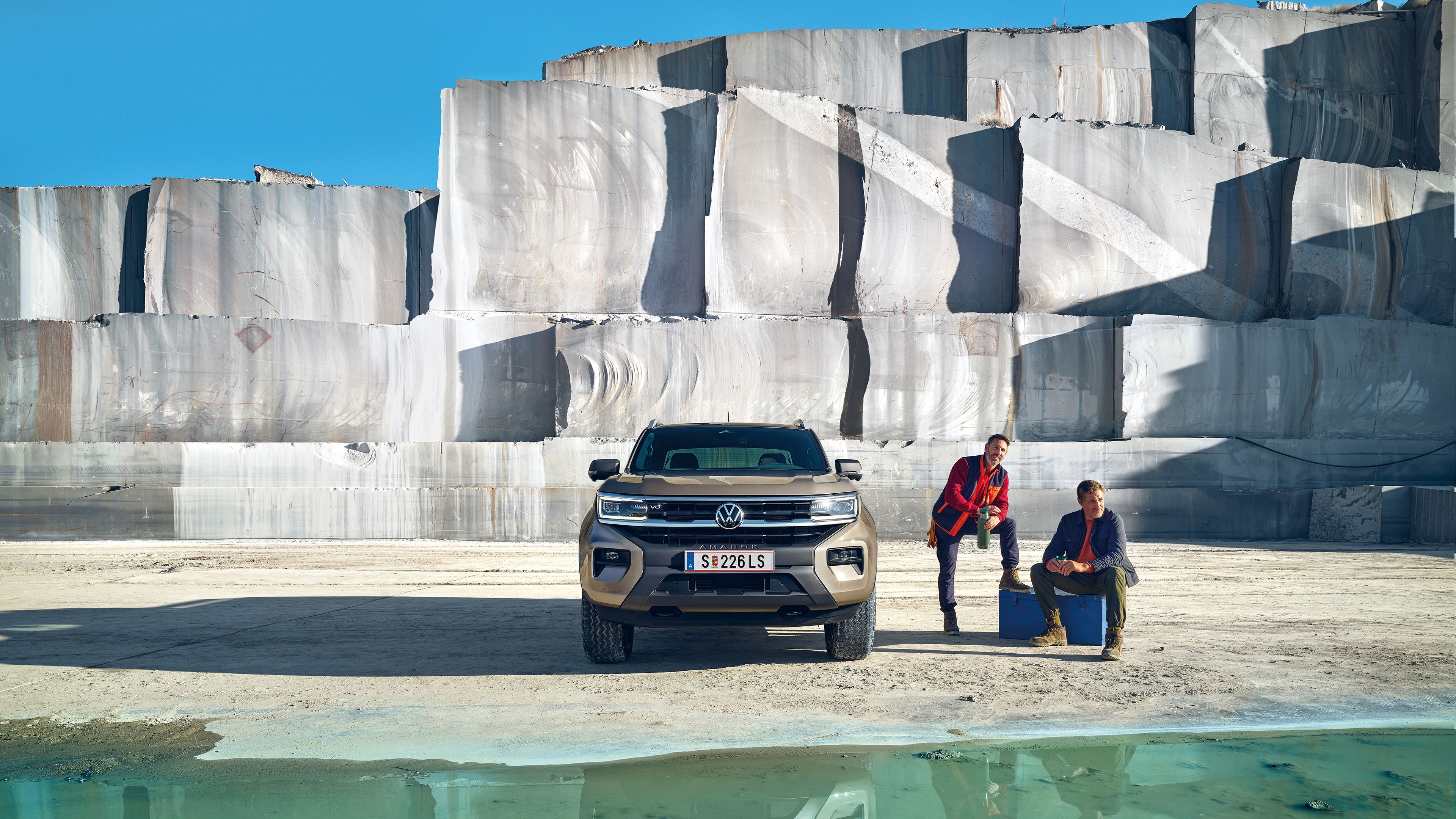 Der neue VW Amarok steht im Freien neben zwei Männern