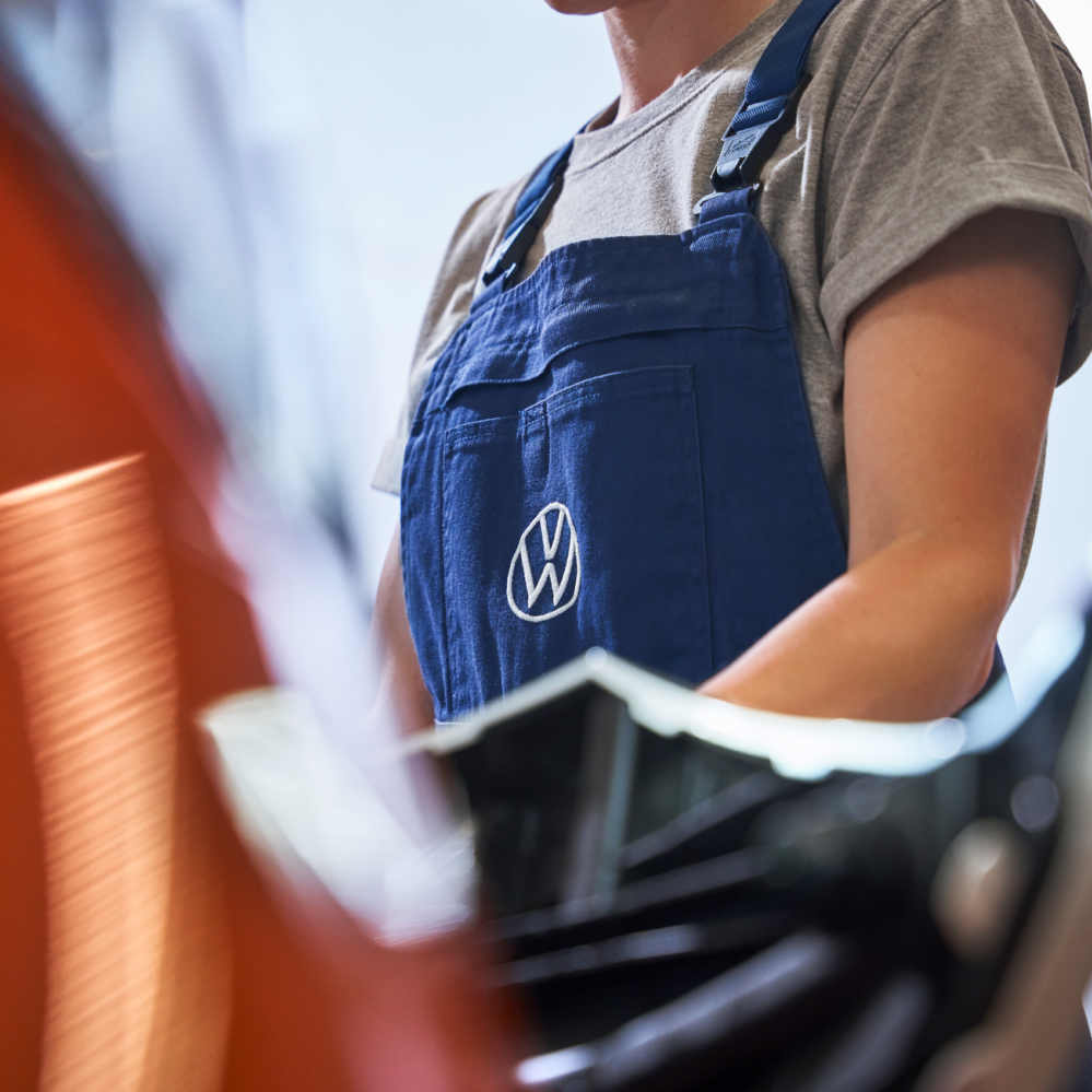 Fokusansicht des Volkswagen Logos der Arbeitskleidung einer Volkswagen Technikerin